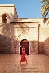 Marrakech Prints: Lady in traditional dress in front of door at Koutoubia Mosque, Marrakech, Morocco