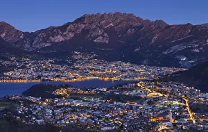 Plain Prints: Lecco lights up at dusk from the Plain of San Tomaso, lake Como, Lombardy, Italy, Europe