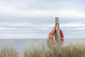 Northumberland Prints: Lifebuoy rings hanging on a post in sand dunes