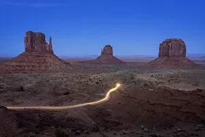 Light trail from car driving on scenic drive road near The Mitten Buttes in Monument