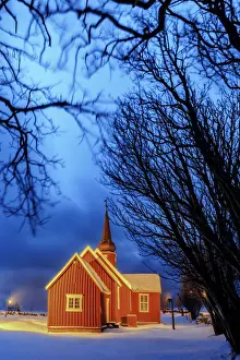 Lights on the church at dusk with the snowy peaks in the background Flakstad Lofoten