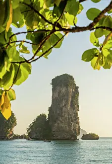 Limestone Karst tower framed by trees on Pai Plong Beach, Ao Nang, Krabi, Thailand