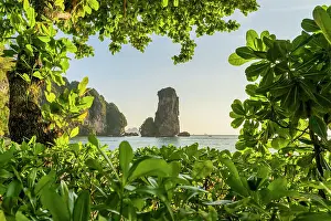 Limestone Karst tower framed by trees on Pai Plong Beach, Ao Nang, Krabi, Thailand
