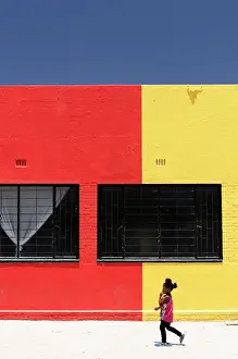 Namibia Prints: Little girl walking past colourful painted building, Kalkrand, Hardap Region, Namibia