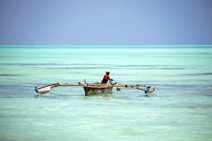 Zanzibar Prints: Local fisherman bailing out his old wooden dhow, Nungwi, Zanzibar, Tanzania