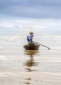 Local fisherman casting the fishing net from the boat, near Hoi An, Vietnam