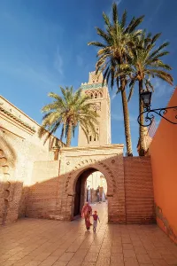 Tall Building Prints: Local lady and child walking through doorway at Koutoubia Mosque, Marrakech, Morocco