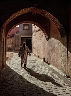 Cobbled Street Prints: Local man in djellaba, walking through an archway on cobbled street