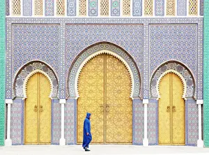 Royal Palace Prints: Local man wearing blue Djellaba walking past the golden doors of the Royal Palace