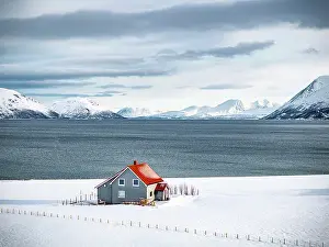 Fjord Prints: Lone traditional house by the fjord in the snowy winter landscape