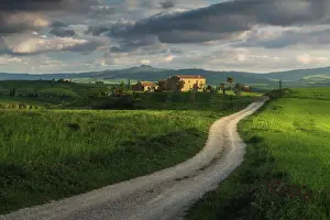 Rolling Hills Prints: A lonely countryhouse on a cloudy spring afternoon gets illuminated by the evening sun in Val d'Orcia