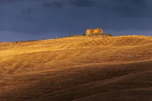A lonely countryhouse and some rolling hills illuminated by the warm sunset light in autumn