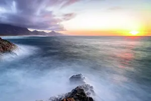 Rippled Prints: Long exposure of waves crashing on rocks surrounding Cofete Beach at sunset