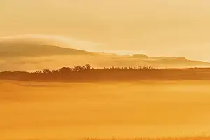 Sunrise Sunset Prints: Looing east at sun rising over the prairie in fog Waterton Lakes National Park