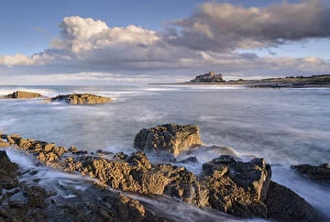 Images Dated 20th July 2017: Looking across rocky ledges to Bamburgh Castle, Northumberland, England