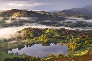 Loughrigg Tarn surrounded by misty autumnal countryside, Lake District, Cumbria, England Loughrigg Tarn surrounded by misty autumnal countryside, Lake District, Cumbria, England
