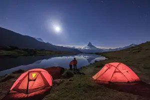 Light Prints: Lovers admire Matterhorn reflected in Lake Stellisee on a starry night of full moon