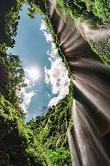 Tropical Climate Prints: Low angle view of water cascades down the lush towering walls of Madakaripura waterfall