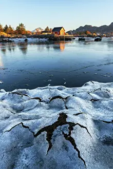 Cabins Prints: Low tide ice patterns and a solitary wooden house along the shore of the fjord seen at sunrise