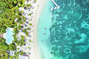 West Indies Gallery: Luxury resort with swimming pool and beach umbrellas on palm fringed beach from above, Antigua