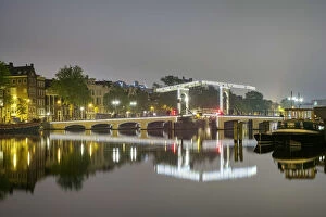 Magere Brug over the river Amstel illuminated at night on foggy evening, Amsterdam