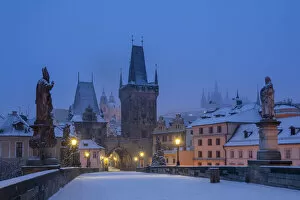 Mala Strana Bridge Tower at snow-covered Charles Bridge at twilight in winter, Prague