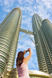 Images Dated 24th January 2012: Malaysia, Kuala Lumpur, Petronas Towers, Woman photographing towers MR