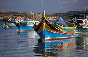 Malta, Europe; Colourful traditional Maltese boats known locally as luzzu in the village of Marsaxlokk which is still based around the fishing industry. The boats have two eyes in the bow which according to legend might represent those