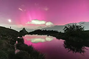 Aurora Borealis Prints: Man admiring the sky with Northern Lights reflected in an alpine lake