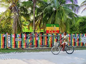 Cycling Prints: Man biking in front of the Rastafarian Community at Caye Caulker Village