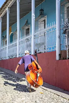 Music Gallery: A man carrying a cello in Plaza Mayor in Trinidad, Sancti Spiritus, Cuba