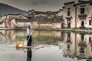 Man collecting rubbish in pond, Hongcun, China