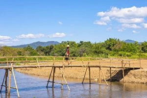 A man crossing a bridge over a river in Pai, Mae Hong Son province, Northern Thailand
