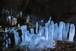 A man at Grotta dei Pagani with illuminated stalactites and stalagmites during night, Castione della Pesolana