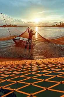 Orange Prints: Man handling the fishing net suspended over a river