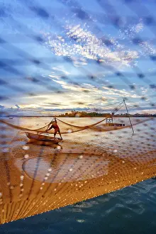 Quang Nam Province Prints: Man handling fishing nets suspended over a river