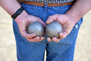 Game Prints: A man holds two boules whilst he plays petanque, Dordogne, Nouvelle-Aquitaine, France