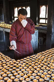 Prayer Gallery: A man lighting candles in a shrine in Jambey Lhakhang, Jakar, Bumthang District, Bhutan