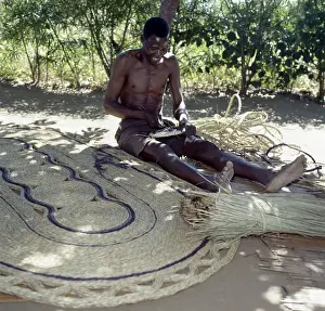 A man makes attractive floor mats from dried palm fronds near Liwonde