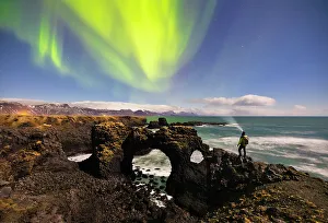 Images Dated 1st June 2023: A man observes Gatklettur arch and northern lights, Arnarstapi, Snaefellsnes peninsula