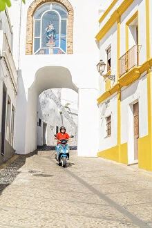 Images Dated 22nd May 2023: Man riding a scooter through Puerta de Matrera, Arcos de la Frontera, Andalusia, Spain
