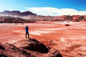 Red Rocks Prints: Man on rocks photographing the red Devil's Desert, Puna, Argentina. (MR)