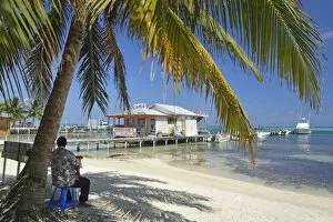 Images Dated 22nd May 2013: Man sat under a palm on the beach at San Pedro, Ambergris Caye, Caribbean, Central