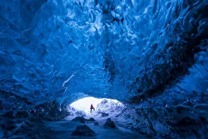 Man standing at entrance to an ice cave beneath a glacier, Iceland, Europe