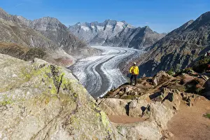 Standing Prints: Man standing on top of a rock observing the alpine landscape of the Aletsch glacier