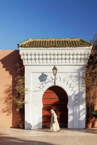 Tall Building Prints: Man in traditional dress walking in front of door at Koutoubia Mosque, Marrakech, Morocco