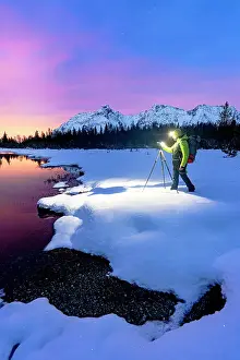 Beauty Prints: Man with tripod photographing lake Entova at dawn standing on the snowy shores