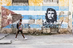 A man walking in a front of Che Guevara street art in La Habana Vieja (Old Town), Havana