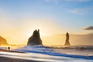 Man walking past the Sea Stacks at Reynisfjara black sand beach, Vik, Iceland, Europe