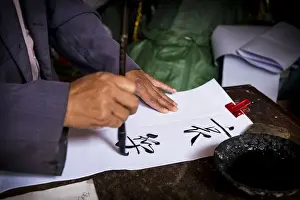 Yunnan Prints: Man is writing with chinese idioms at Shigu Village or Stone Drum Village, Lijiang